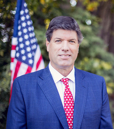 Man in blue suit standing in front of American flag